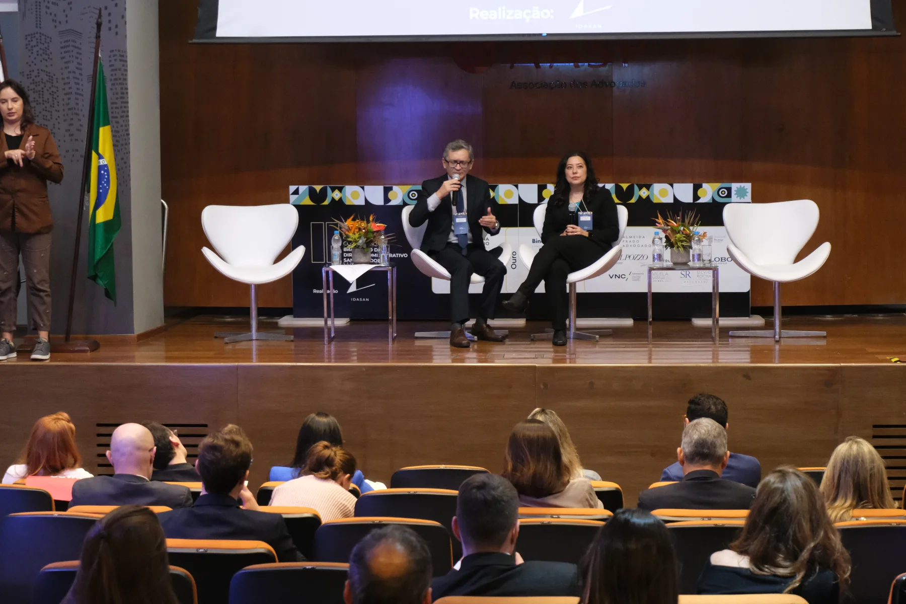 Palco do congresso com painel e público acompanhando a programação.